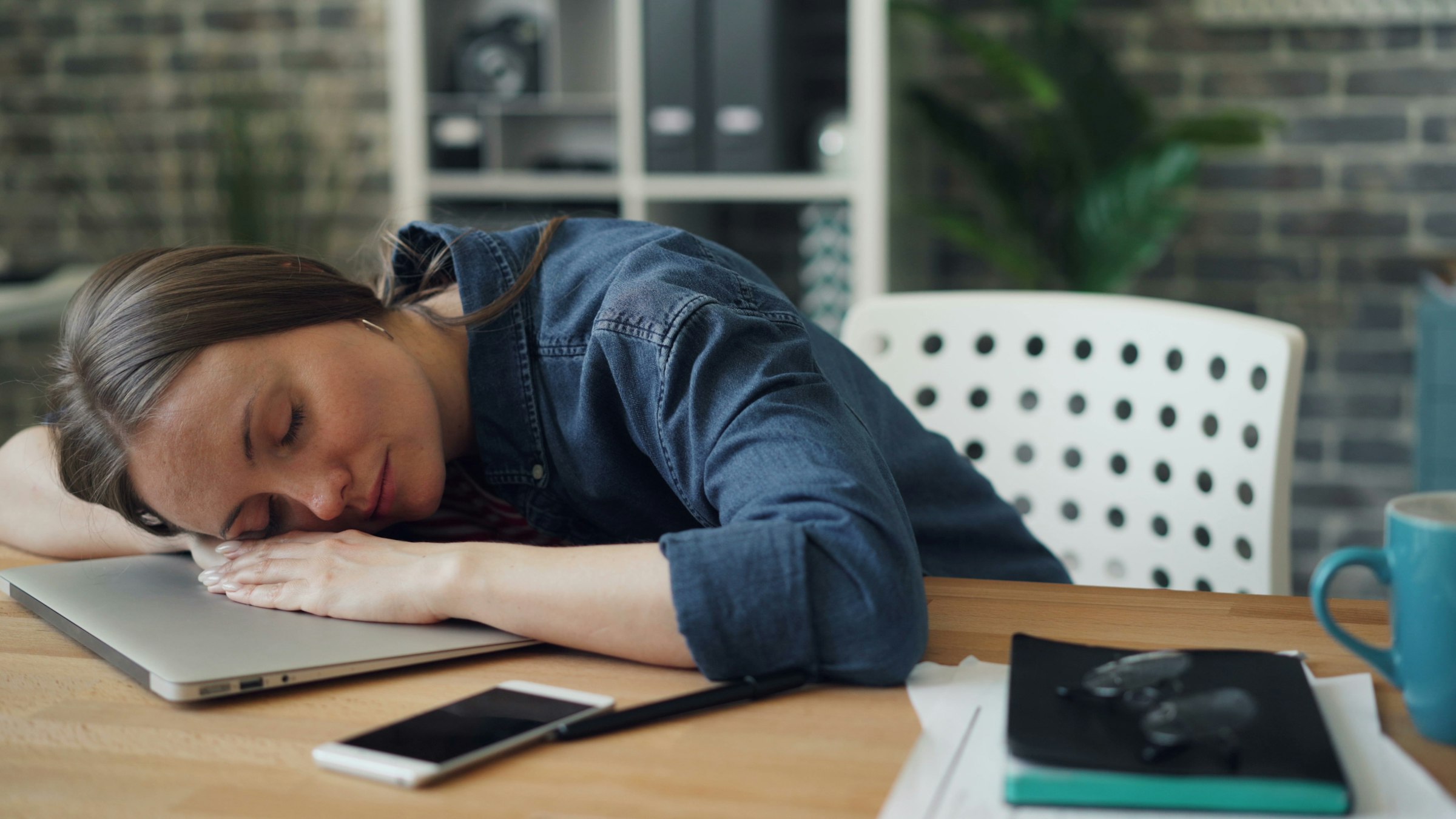 Exhausted woman slumped at laptop