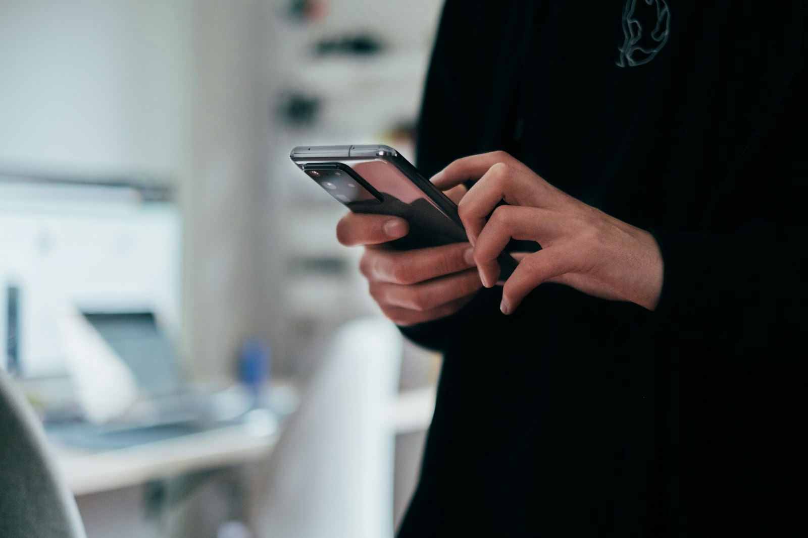 Person holding a smartphone with both hands, screen facing away