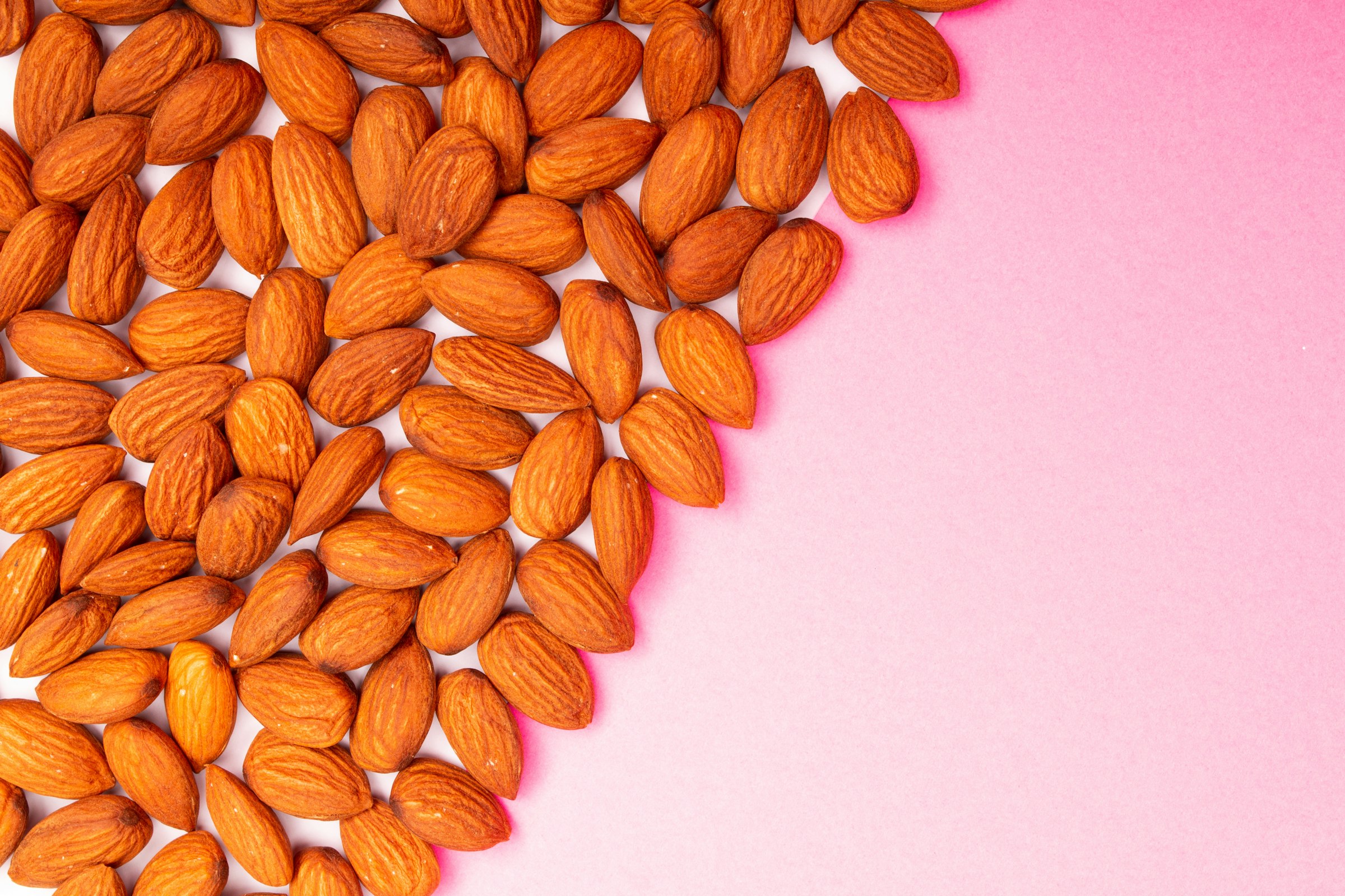 Almonds arranged on a pink background