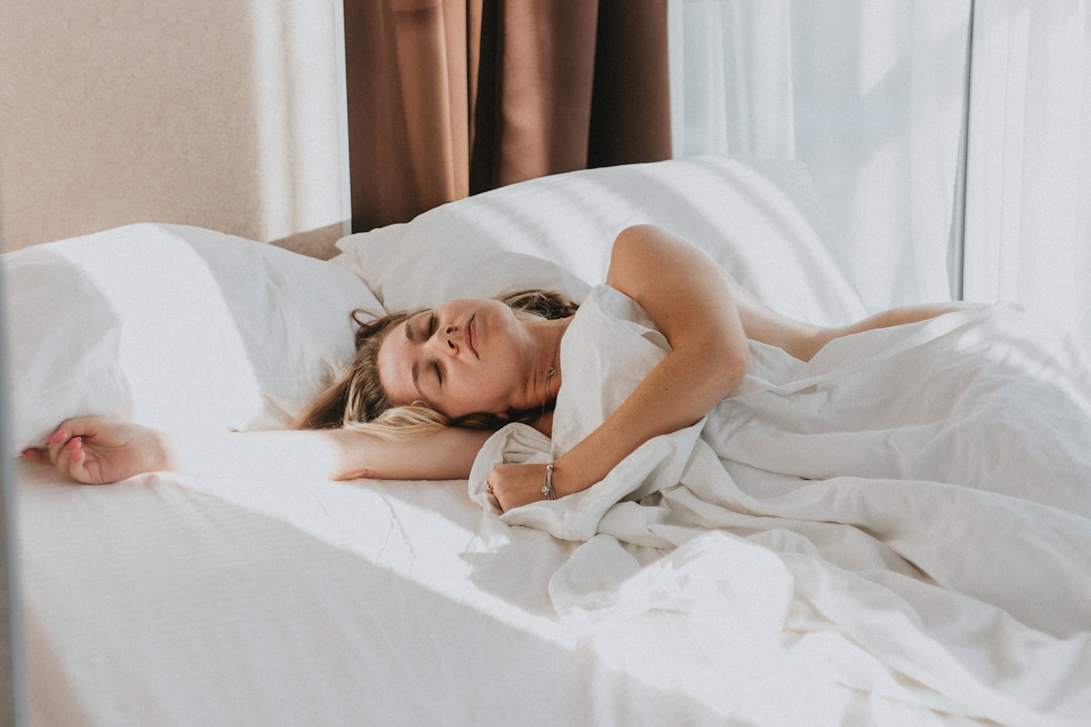 Person resting peacefully in a bed with soft ambient lighting