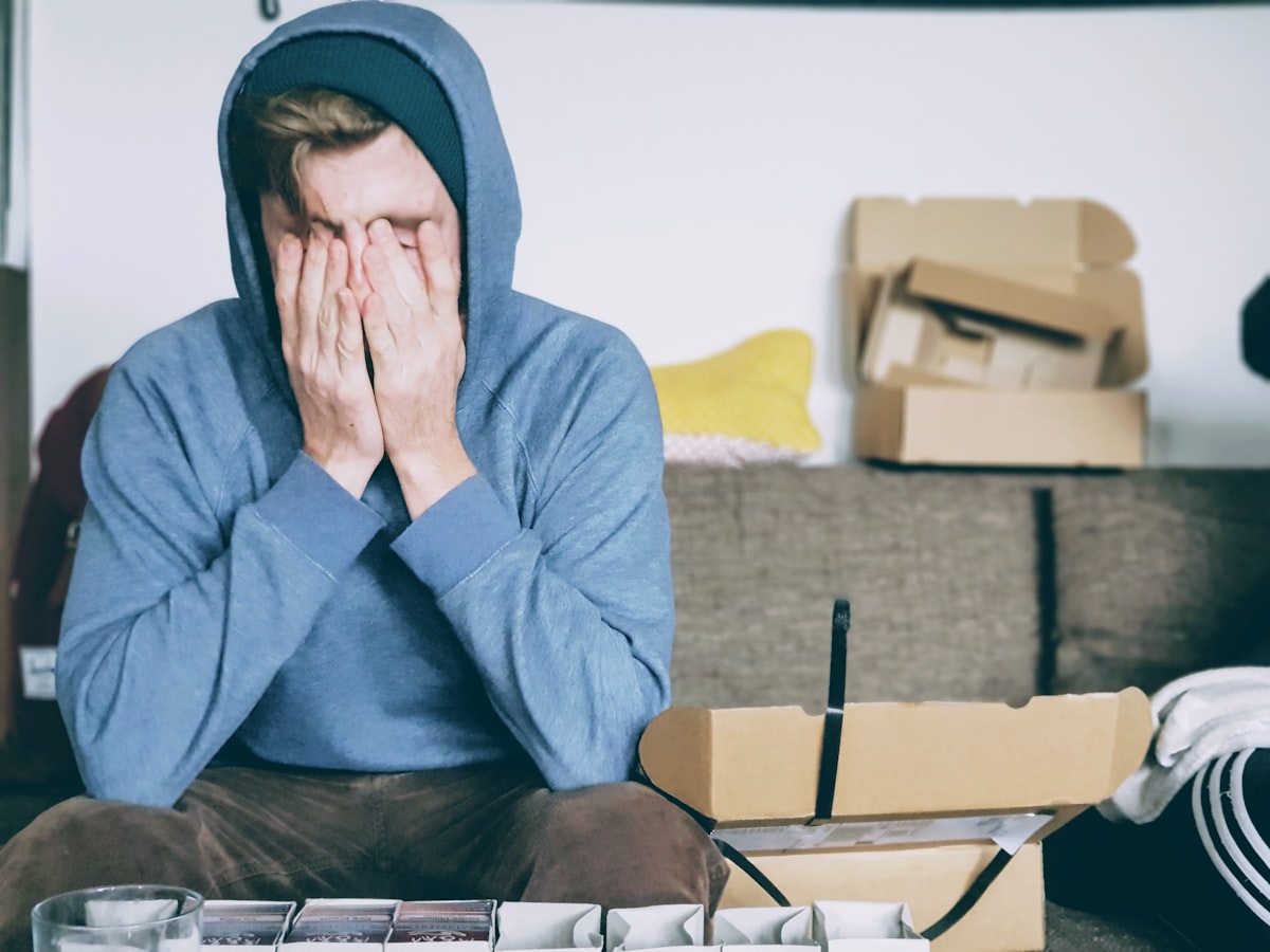 Person sitting alone covering face with hands, showing emotional overwhelm and stress